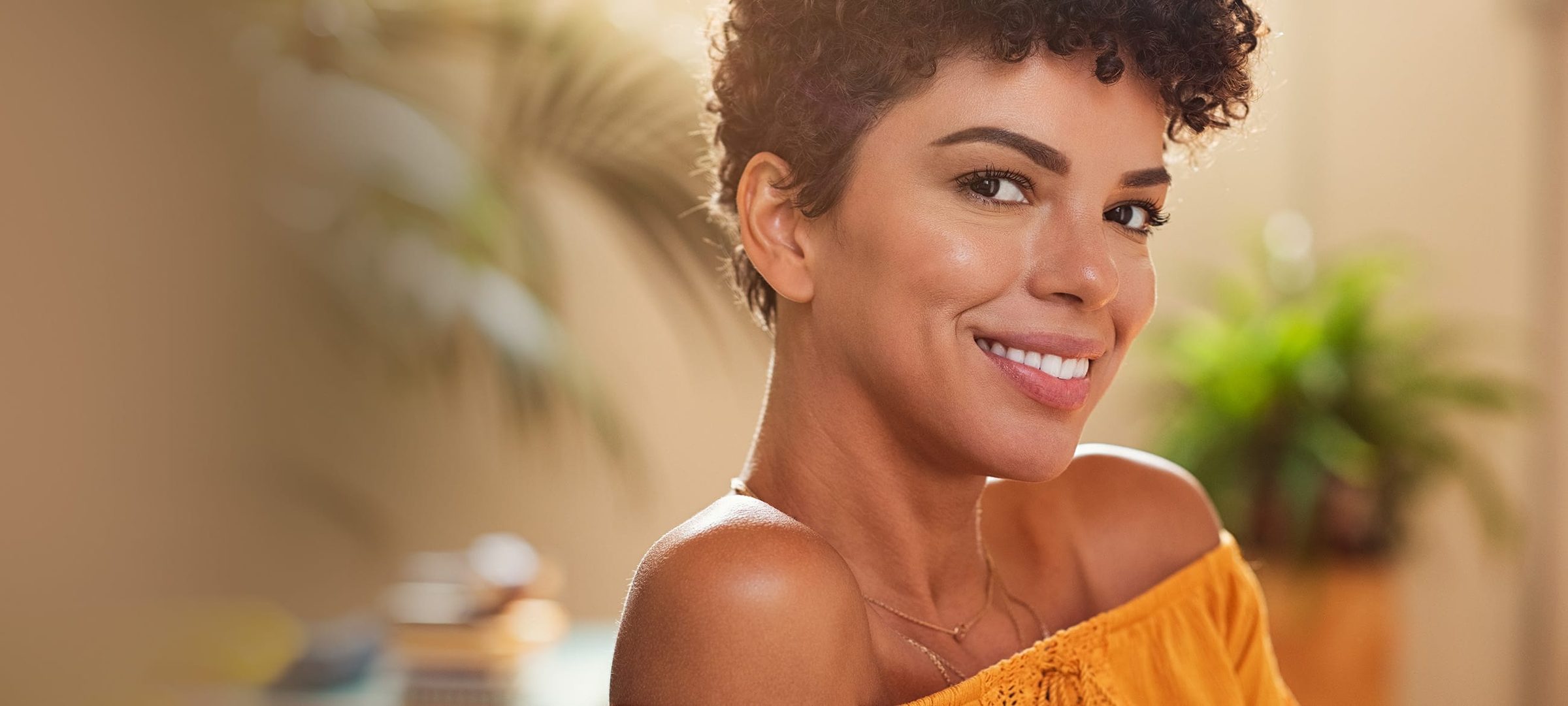 Woman with short curly hair wearing an orange top