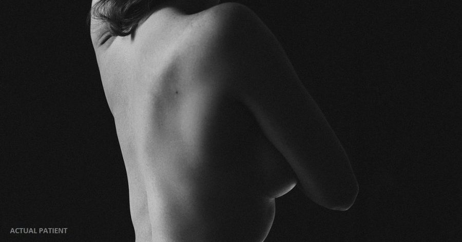 woman with long hair and no shirt standing in front of a black background