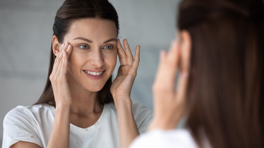 A woman looking in the mirror touching her face